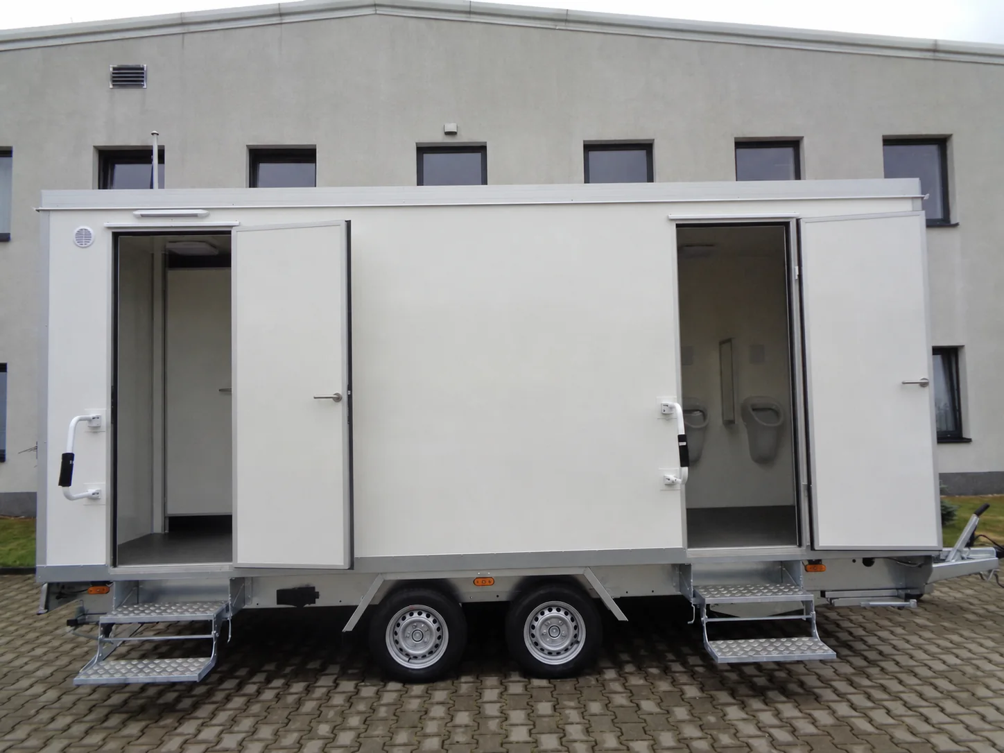 Toilettenanhänger Typ 3+1+3-52 mit geöffneten Sanitärtüren und Tandemachse in Seitenansicht